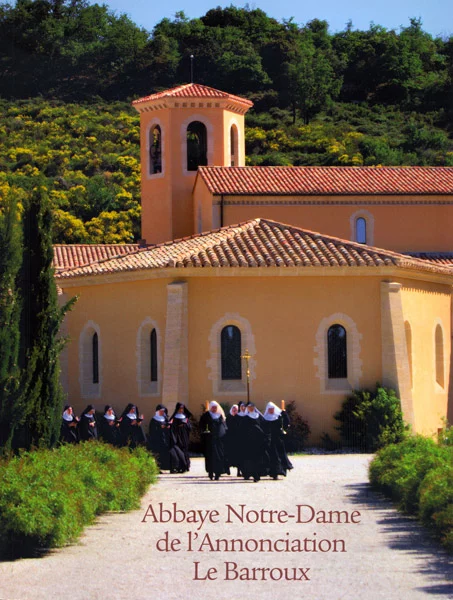 Procession de moniales devant l'Abbaye Notre-Dame de l'Annonciation au Barroux, avec clocher et toits rouges sous le soleil de Provence.
